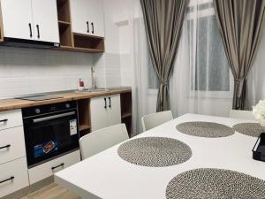 a kitchen with white cabinets and white tables and chairs at Cristal Residence in Zalău