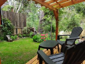 een terras met een tafel en stoelen op een dek bij Cabañita del bosque in Bariloche