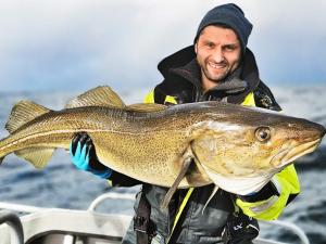 a man holding a fish in a boat at 4 person holiday home in Rebbenes in Rebbenes