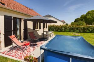 ロミイ・シュル・セーヌにあるMaison du Bien-Êtreの青い防水シートと椅子2脚と傘が置かれたパティオ