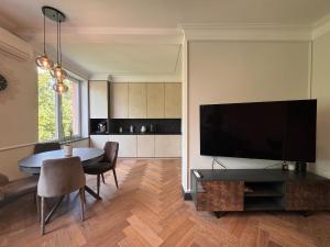 a living room with a table and a large television at Monaco in Šiauliai