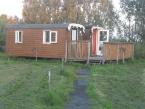 a small cabin in a field with a porch at Bed & Breakfast ARKEN AE in Zuiderwoude