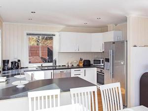 a kitchen with white cabinets and a table with chairs at 4 star holiday home in Lyngdal in Lyngdal