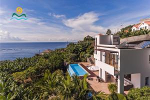 an aerial view of a house with a swimming pool and the ocean at OurMadeira - The Designhouse, contemporary in Arco da Calheta