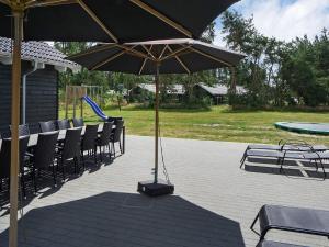 a table and chairs with an umbrella on a patio at 22 person holiday home in Nexø in Bedegård