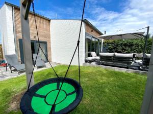a tire swing in the yard of a house at Holiday Home Nieuwvliet near Beach in Nieuwvliet-Bad