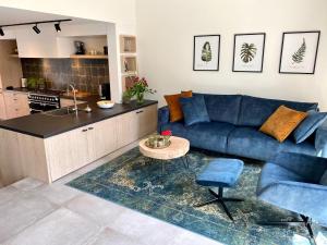 a living room with a blue couch and a kitchen at Holiday Home Nieuwvliet near Beach in Nieuwvliet-Bad +27 photos
