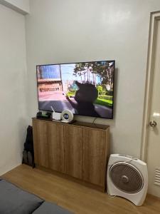 a living room with a flat screen tv and a fan at Cozy 1-BR Unit at The Loop CDO in Pontud