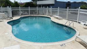 a large swimming pool with a fence and chairs at Flamingo Inn in Kissimmee