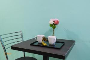 a table with two cups and a vase with flowers at Nature Nine Farmstay Khopoli in Āmbavna