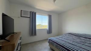 カボ・フリオにあるDunas do Peró, Cabo Frio 01のベッドと薄型テレビのある寝室