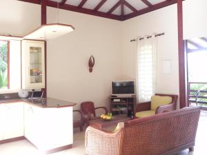 a living room with a couch and a tv at Villa MIELéCAJOU, entre mer et montagne in Deshaies