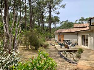 une maison avec un porche et une terrasse avec des chaises dans l'établissement Chic Retreat by the Dunes, à Carcans