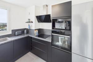 a kitchen with black cabinets and stainless steel appliances at Le Balcon de Gallieni in Sainte-Savine