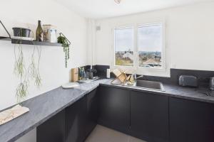 a kitchen with black cabinets and a sink and a window at Le Balcon de Gallieni in Sainte-Savine +3 photos