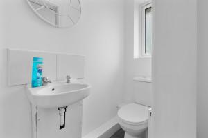 a white bathroom with a toilet and a sink at 6 Bedrooms, Driveway Parking, Pool Table, Netflix, Huge Long Term Savings in Great Sankey