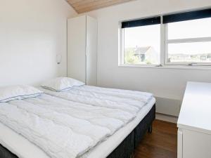 a white bedroom with a large bed with a window at 4 star holiday home in Brovst in Brovst