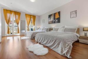 a white bedroom with two beds and a wooden floor at Exclusive Apartment in Centre in Bratislava