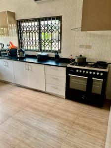 a kitchen with a black stove and white cabinets at Luxe on the lane in Kwedonu