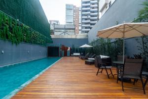 a swimming pool with tables and chairs and an umbrella at Higienópolis The Standard Residence in São Paulo +30 photos