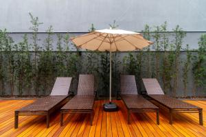 a patio with three chairs and an umbrella at Higienópolis The Standard Residence in São Paulo