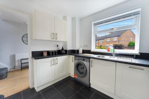 a kitchen with white cabinets and a washing machine at City Centre House with Secure Driveway Parking, Neflix, Garden, Long Stay Savings in Liverpool
