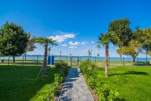 un chemin à travers un parc planté de palmiers dans l'établissement MyFlat Sunton Apartment, à Siófok