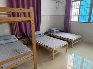 two bunk beds in a room with purple curtains at Dongfang City Erlihai Youth Hostel 