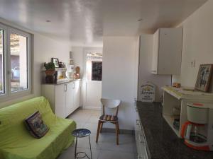 a kitchen and a living room with a green couch at La maison de Quitterie in Aire-sur-lʼAdour