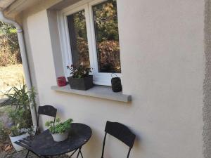 eine Terrasse mit einem Tisch, 2 Stühlen und einem Fenster in der Unterkunft La maison de Quitterie in Aire-sur-lʼAdour