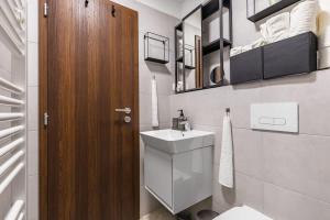 a bathroom with a toilet and a sink and a wooden door at Modern and Cozy flat with Balcony in Bratislava