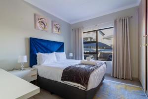 Un dormitorio con una cama con cabecero azul y una ventana. en #AlimamaSpaces The Manson Umthunzi View, en Vosburg 50 fotos más