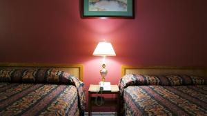 a hotel room with two beds and a lamp on a table at Blue Jay Motel in Peterborough