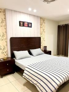 a bedroom with a large bed with a striped blanket at Luxe 1BHK Apartment with Pool and Sauna in Islamabad