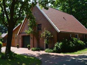 a red brick house with a tree in front of it at Lindern Woodland Mansion in Werlte