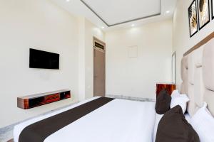 Un dormitorio con una cama y un televisor en la pared. en Super Hotel O BAL GOPAL, en Delhi 29 fotos más