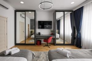 a bedroom with two beds and a desk and a mirror at Eden Central Boutique Suites - Garden & Spacious Apartments in Cluj-Napoca