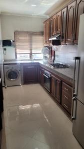 a kitchen with wooden cabinets and a washer and dryer at Bel Appartement spacieux 3 pièces avec double salon Paisible & Proche de la Gare d'Agdal in Rabat
