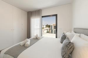 a white bedroom with a large bed and a window at Lua Tranquilizante in Foz do Arelho