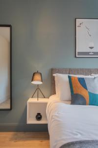 a bedroom with a bed with a lamp and a mirror at Camden Luxe Apartments in Belfast