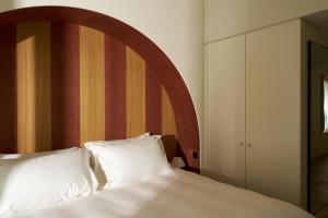 a bed with white pillows and a wooden headboard at Auberge Port Gitana in Bellevue