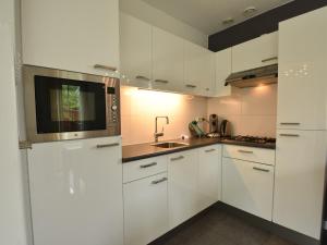 a kitchen with white cabinets and a microwave at Wellness aan het Water in Earnewoude in Earnewâld