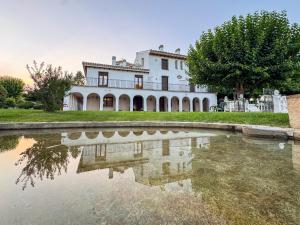 a large white house with a reflection in a pond at Complejo El Molinico in Puebla de Don Fadrique