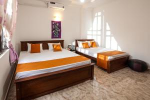 um quarto com 2 camas com almofadas laranja em V&C Hideout Villa & Hostel em Kandy
