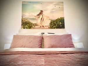 a painting hanging above a bed with pink pillows at Elegant apartment in Kosice in Košice
