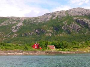 a red house in front of a mountain at 6 person holiday home in Vevelstad-By Traum in Vevelstad