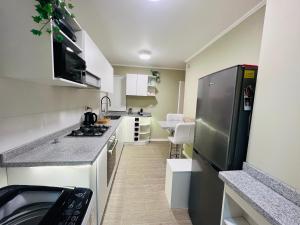 a small kitchen with a stainless steel refrigerator at Alojamiento Casa Puerto Varas, Cerca del lago in Puerto Varas