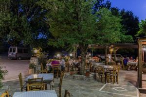 a group of people sitting at tables under a tree at Neos Omalos Hotel in Omalos