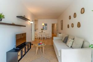 Una sala de estar con un sofá blanco y un televisor de pantalla plana. en 1820 - AB Gaudí Avenue Apartment, en Barcelona