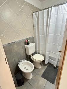 a bathroom with a toilet and a shower curtain at La Ribera in Concepción del Uruguay +4 photos